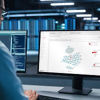 Ein Mann sitzt vor einem Desktop-PC im Serverraum