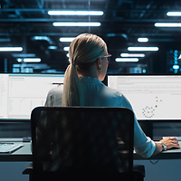 Eine Frau sitzt vor einem Desktop-PC im Serverraum