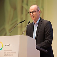 Markus Geisenberger spricht am Rednerpult mit zwei Mikrofonen bei der Messe protekt; auf dem Pult steht das Logo und der Schriftzug „protekt – konferenz für den schutz kritischer infrastrukturen“. Markus Geisenberger spricht am Rednerpult mit zwei Mikrofonen bei der Messe protekt; auf dem Pult steht das Logo und der Schriftzug „protekt – konferenz für den schutz kritischer infrastrukturen“.