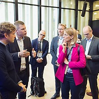 Ein Mann spricht auf der protekt 2024 mit einer Gruppe von Personen in einem modernen Konferenzraum mit Glasfassade; eine Frau in pinkem Blazer steht im Mittelpunkt der Gruppe. Ein Mann spricht auf der protekt 2024 mit einer Gruppe von Personen in einem modernen Konferenzraum mit Glasfassade; eine Frau in pinkem Blazer steht im Mittelpunkt der Gruppe.